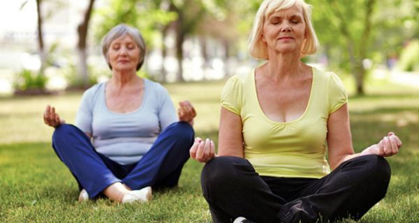 Zwei ältere Frauen meditieren im Park