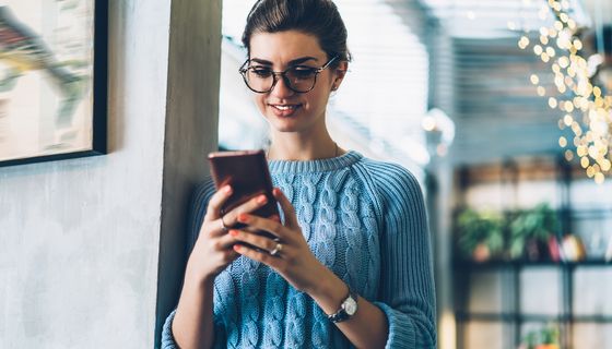 Frau schaut glücklich auf ihr Handy.