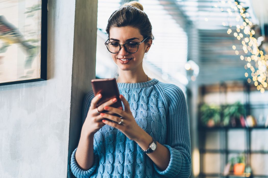 Frau schaut glücklich auf ihr Handy.