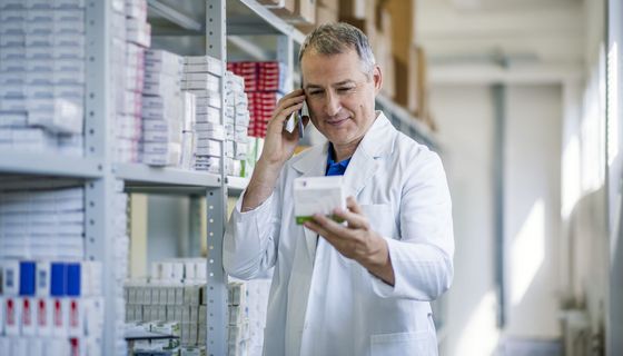 Apotheker, hält ein Medikament in der Hand und telefoniert.