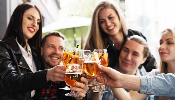 Eine Freundesgruppe stößt mit unterschiedlcihen alkoholischen Drinks an.