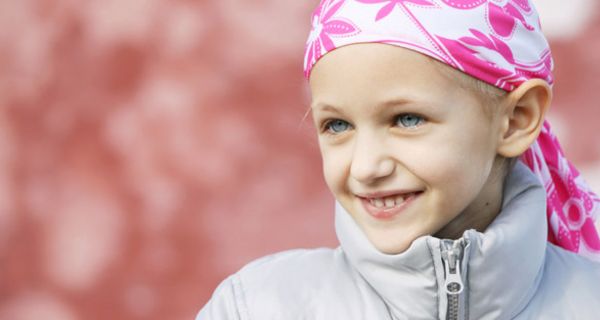 Porträt: Mädchen, ca. 8 Jahre, mit rosaweißgemustertem Kopftuch, schaut nach links aus dem Bild raus. Blaue Augen, leichtes Lächeln
