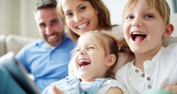 Familie mit zwei Kindern, sitzt zusammen auf dem Sofa. 