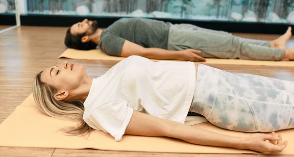 Mann und Frau, liegen auf dem Rücken auf einer Gymnastikmatte.