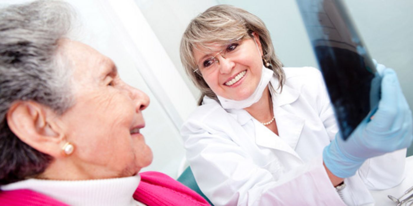 Seniorin mit Zahnärztin, die ihr ein Röntgenbild zeigt