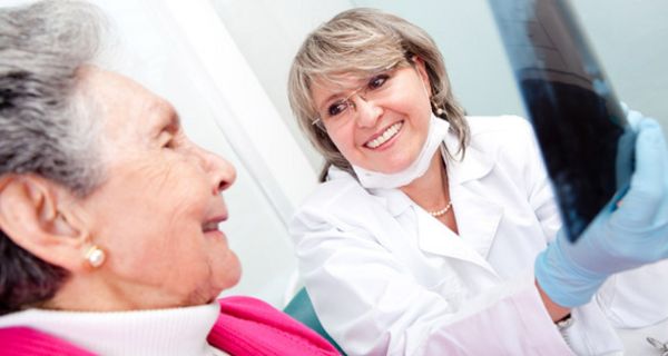 Seniorin mit Zahnärztin, die ihr ein Röntgenbild zeigt