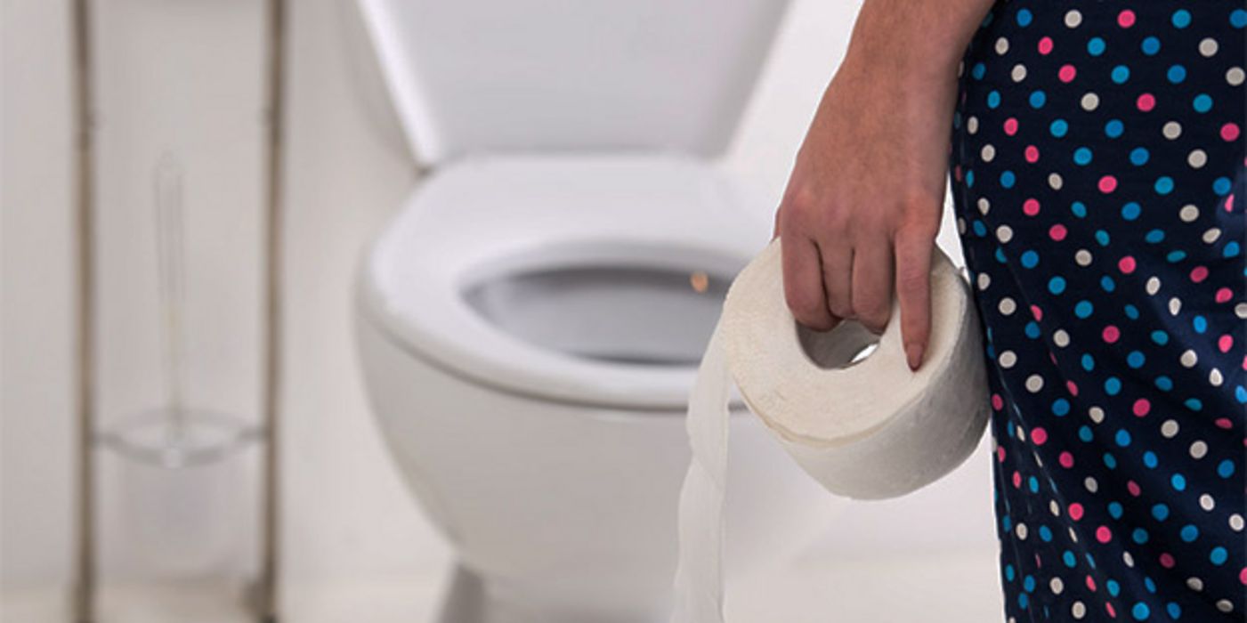 Toilette, weiß, Teilansicht von hinten (rechter Bildrand) Frau in bunter Leggins mit Toilettenpapierrolle in linker Hand