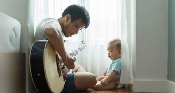 Vater, spielt für sein Kind Gitarre.