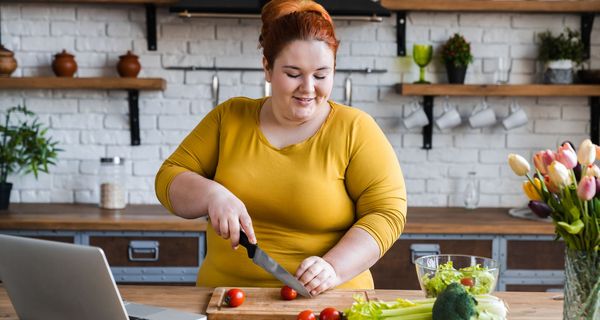 Frau schneidet Gemüse in der Küche