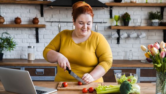 Frau schneidet Gemüse in der Küche
