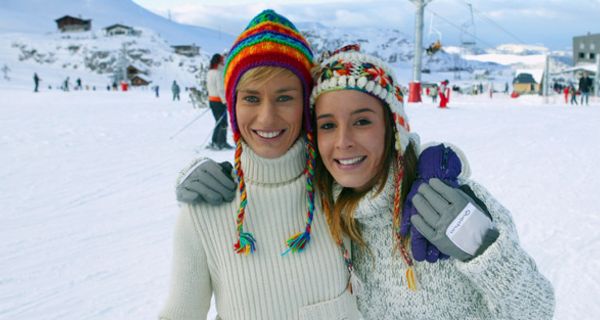 Zwei junge Wintersportlerinnen mit Mützen auf der Piste