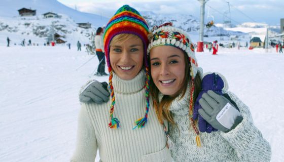Zwei junge Wintersportlerinnen mit Mützen auf der Piste