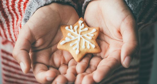 Kinderhand mit verziertem Weihnachtsplätzchen.