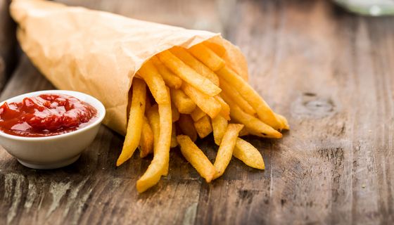 Pommes in einer Tüte, daneben eine Portion Ketchup.