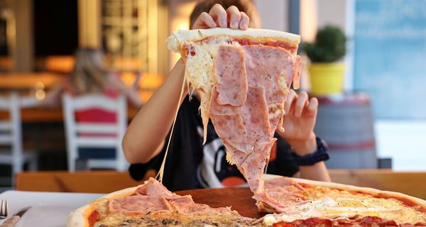 Junge, nimmt sich ein großes Stück Pizza.