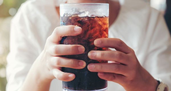 Frau, hält ein Glas Cola in der Hand.