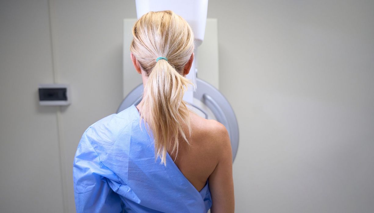 Frau, steht vor dem Mammographie-Röntgenapparat.