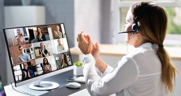 Frau mit Headset in einem Online-Meeting: Alle applaudieren.