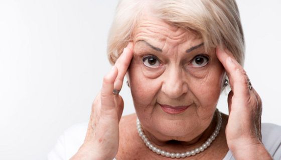 Seniorin hält sich die Schläfen.