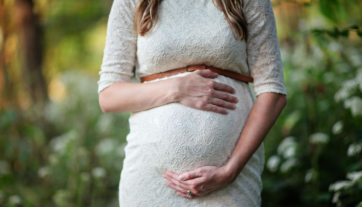 Schwangere Frau greift um ihren Bauch. 