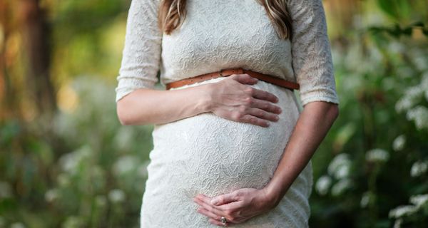 Schwangere Frau greift um ihren Bauch. 