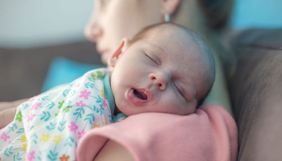 Säugling, liegt auf dem Arm der Mutter und schläft.