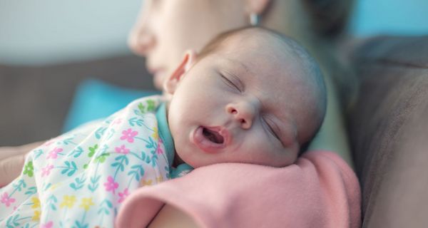 Säugling, liegt auf dem Arm der Mutter und schläft.