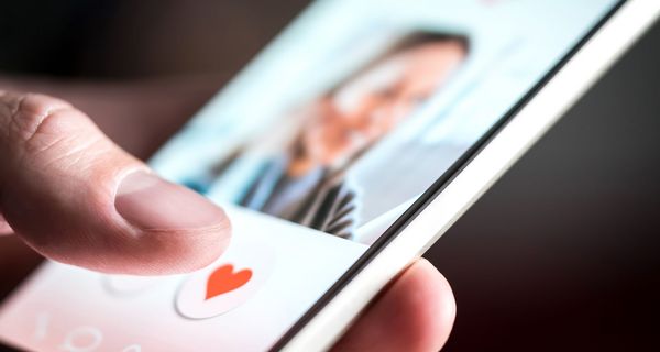 Mann, hält ein Smartphone mit einer Dating App in der Hand. 