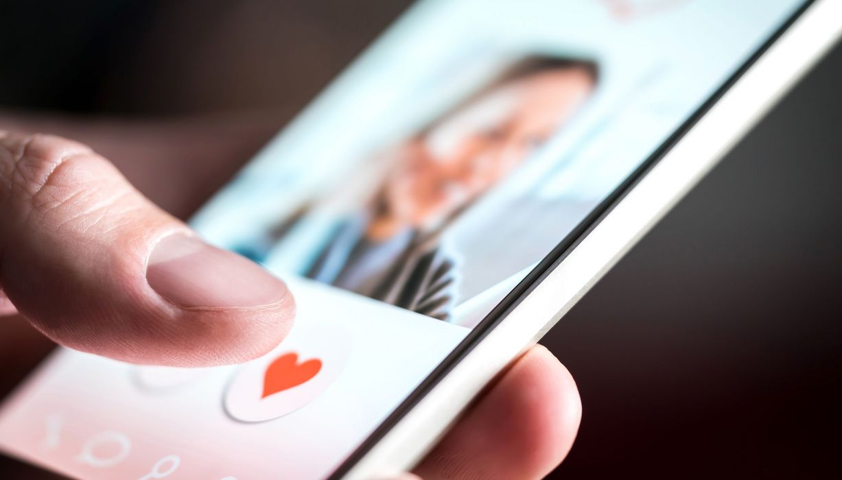 Mann, hält ein Smartphone mit einer Dating App in der Hand. 