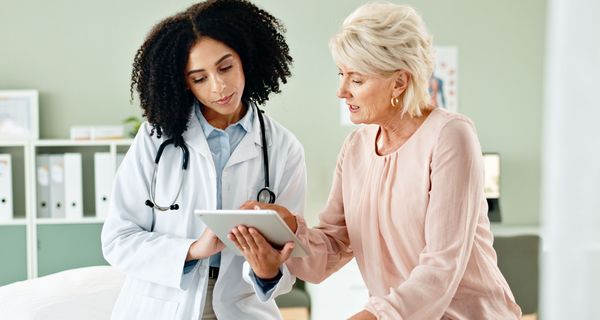 Ärztin zeigt Patientin etwas auf einem Tablet.