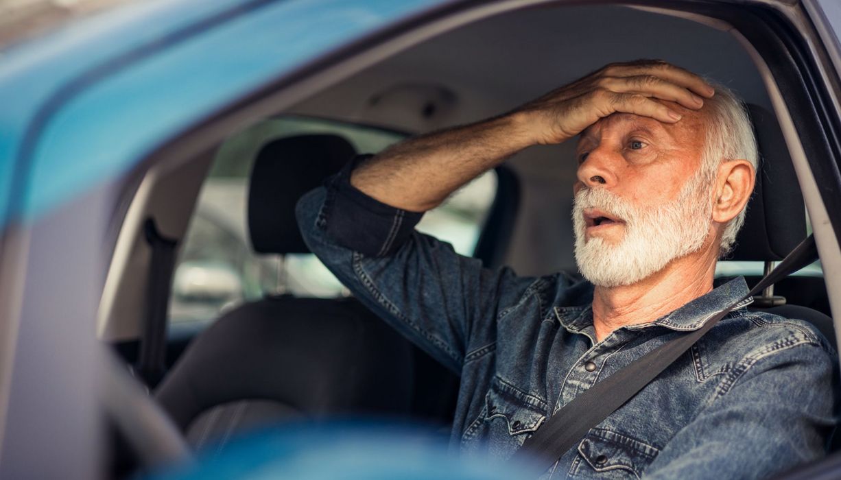 Mann im Lenkrad fasst sich an entnervt an die Stirn.