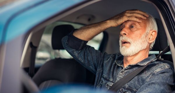 Mann im Lenkrad fasst sich an entnervt an die Stirn.