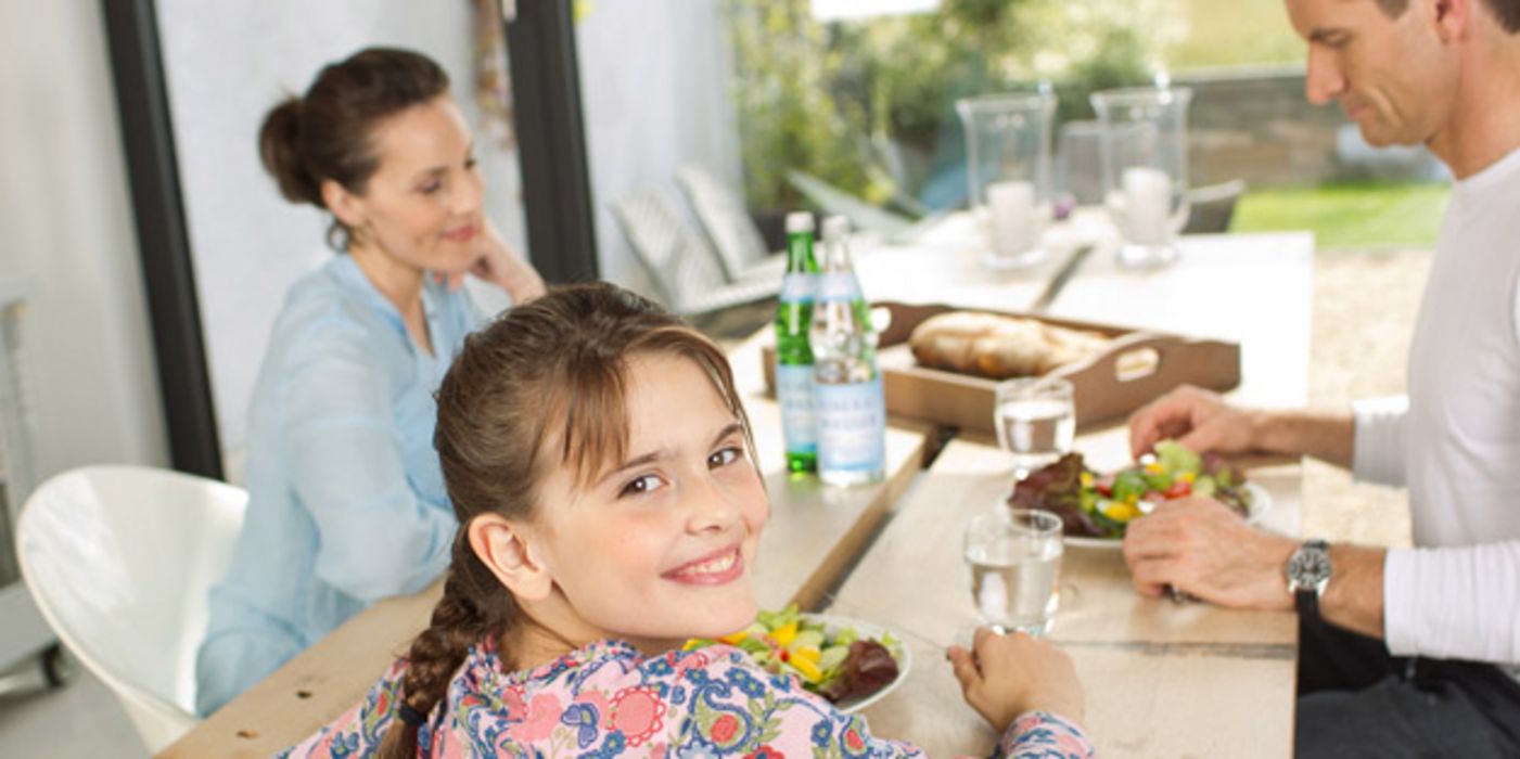 Tisch mit Wassergläsern und Familie beim Essen
