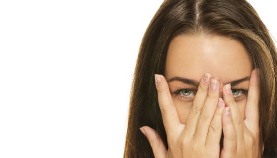 Frau hält sich die Hände vor die Augen und guckt durch die Finger