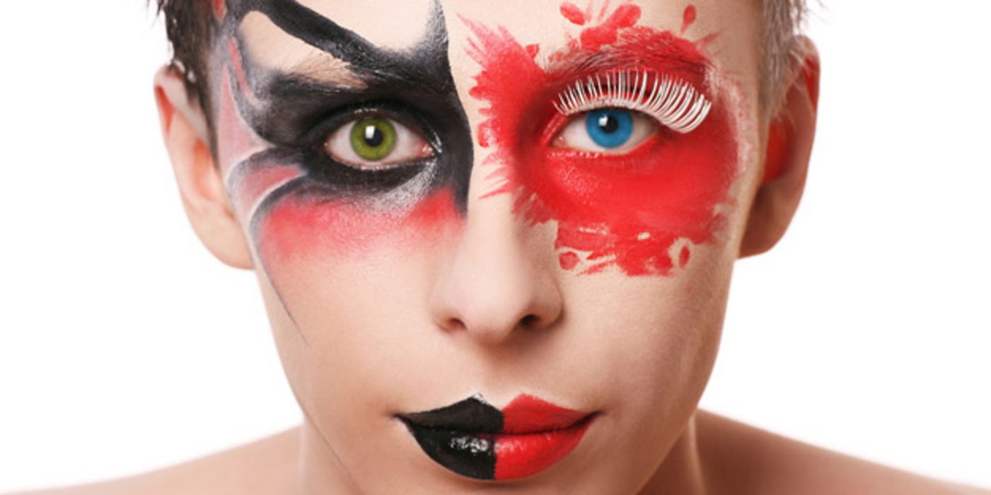 Frontalportrait Frau mit Kontaktlinsen eine grün, eine blau, schwarz-rot-flammiger Augenbemalung und schwarz-roten Lippen