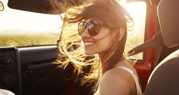 Junge braunhaarige Frau in Cabrio mit Sonnenbrille