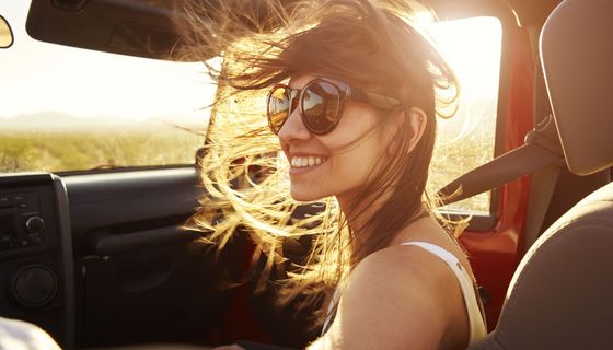 Junge braunhaarige Frau in Cabrio mit Sonnenbrille