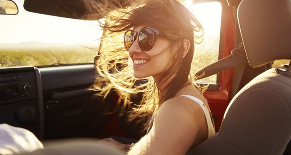 Junge braunhaarige Frau in Cabrio mit Sonnenbrille