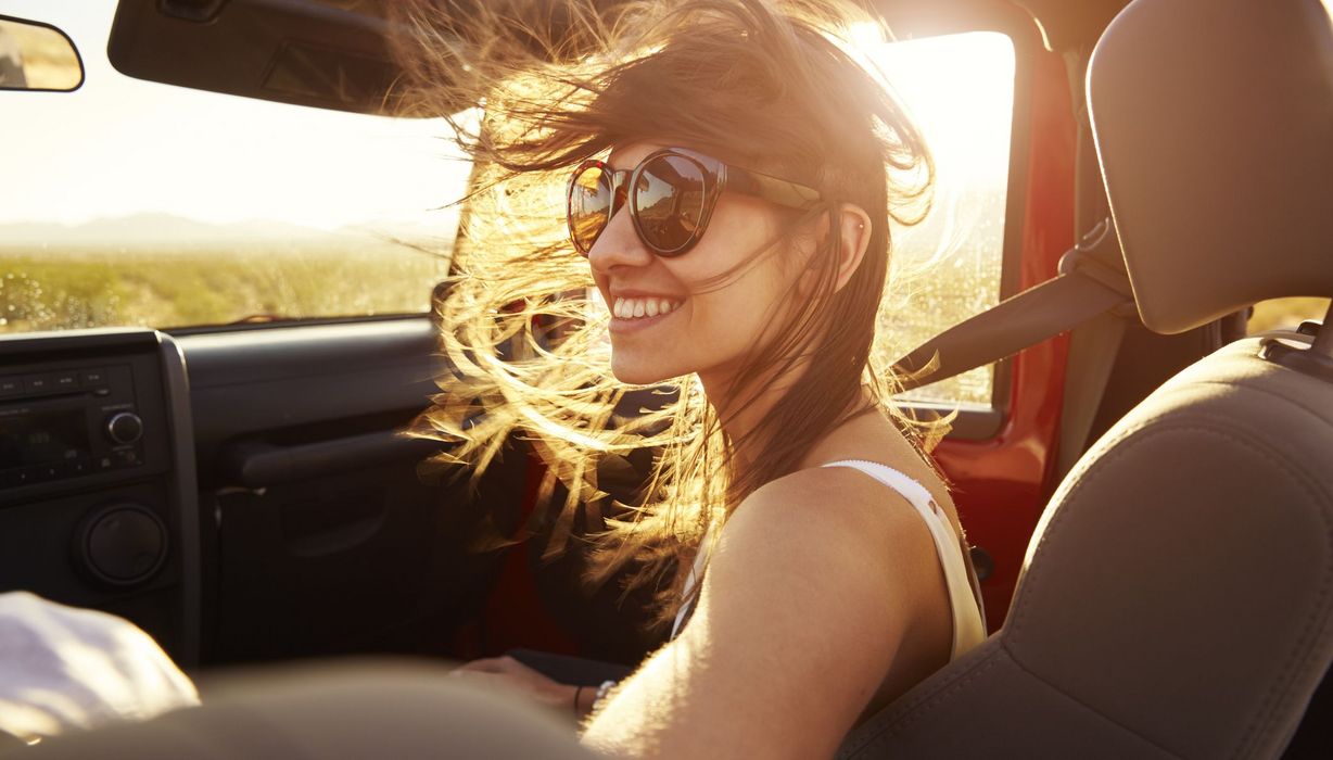 Junge braunhaarige Frau in Cabrio mit Sonnenbrille