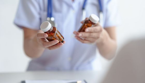 Ärztin mit zwei verschiedenen Tablettendosen in der Hand.
