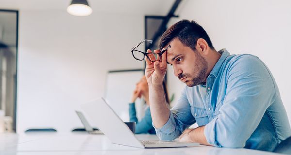 Mann, sitzt angestrengt vor seinem Laptop.