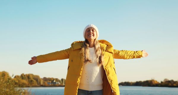Frau mit gelber Daunenjacke in der Sonne