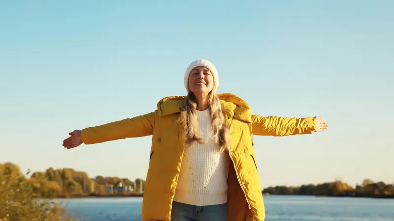 Frau mit gelber Daunenjacke in der Sonne