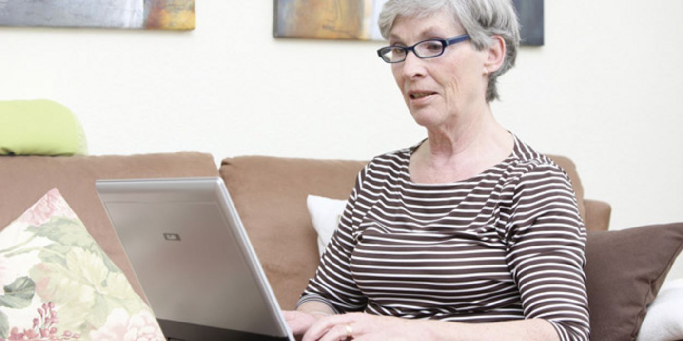 Ältere Frau tippt auf einem Laptop