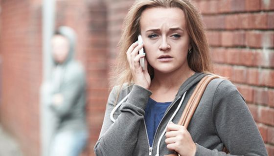 Ängstlich dreinschauende jüngere Frau mit Handy am Ohr