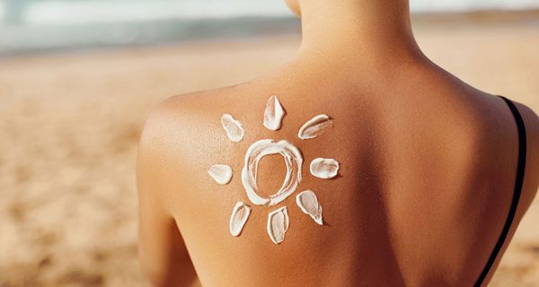 Schulter mit einer Sonne aus Sonnencreme.