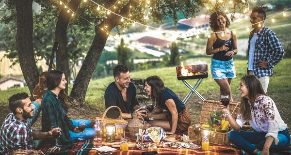 Gruppe von Freunden draußen auf einer Picknickdecke.