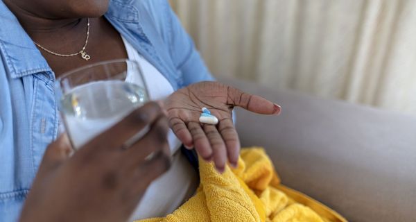 Übergewichtige Frau mit drei Tabletten in der Hand.