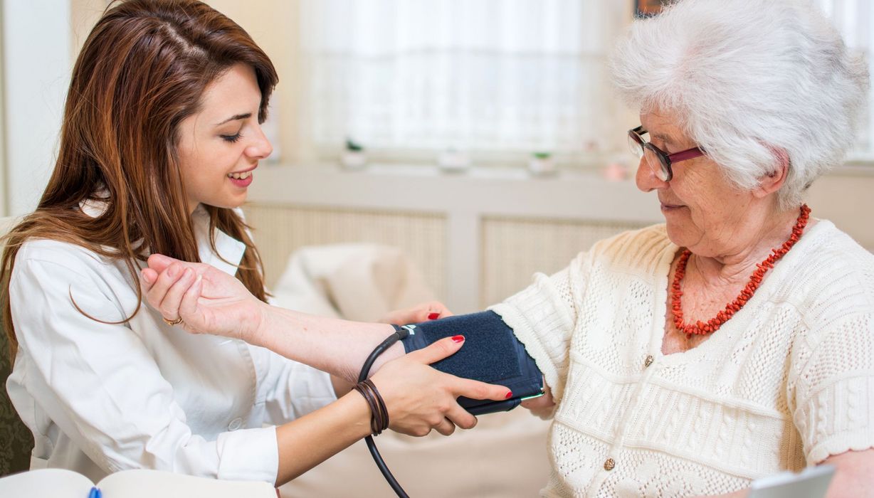 Junge Apothekerin misst Blutdruck bei älterer Frau.