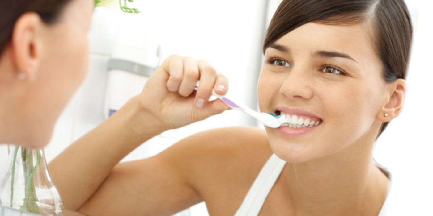 Junge Frau putzt sich die Zähne.